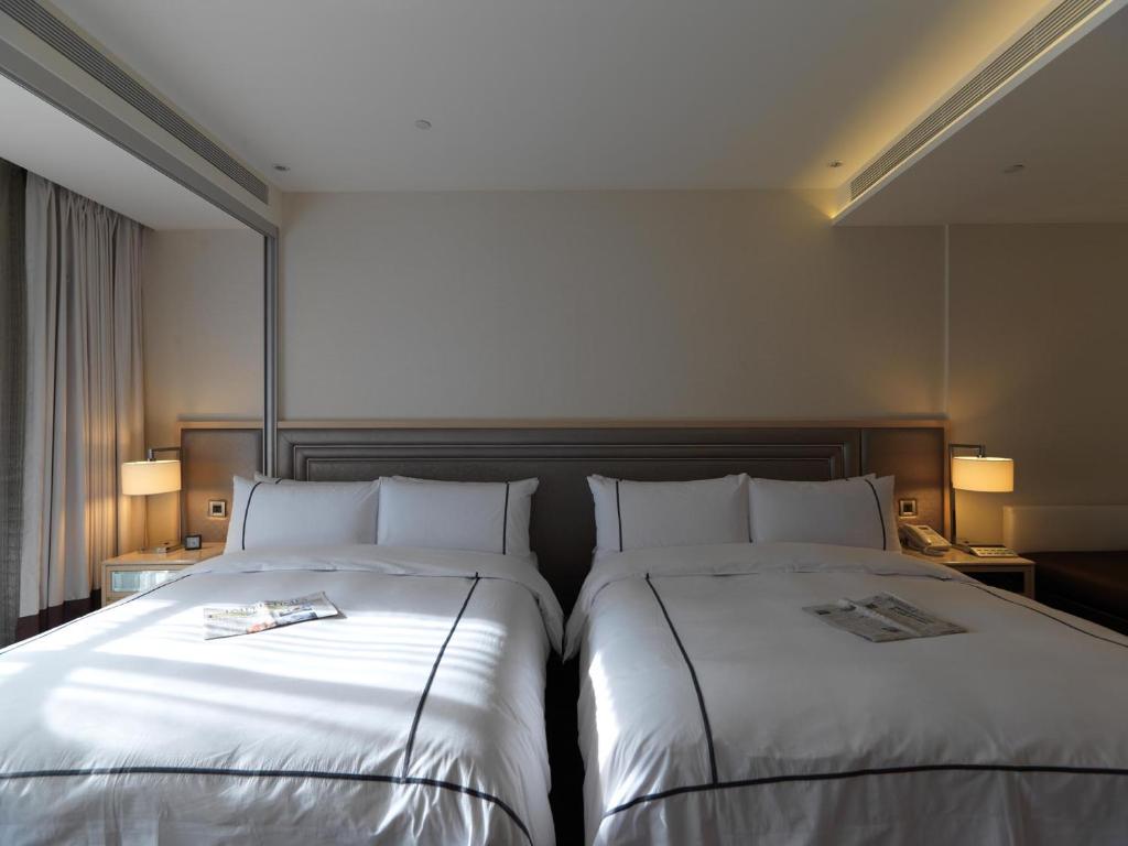 two beds sitting next to each other in a hotel room at K Hotel Taipei Songjiang in Taipei