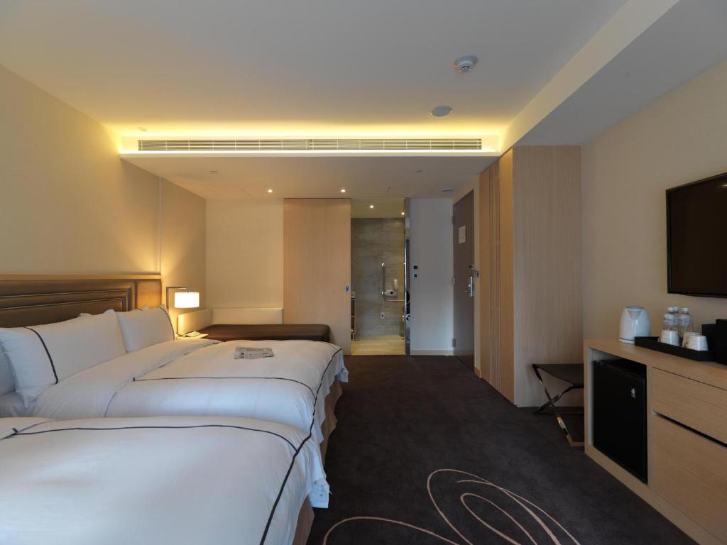 a hotel room with two beds and a flat screen tv at K Hotel Taipei Songjiang in Taipei