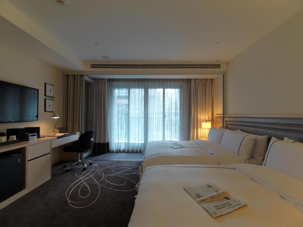 a hotel room with two beds and a television at K Hotel Taipei Songjiang in Taipei