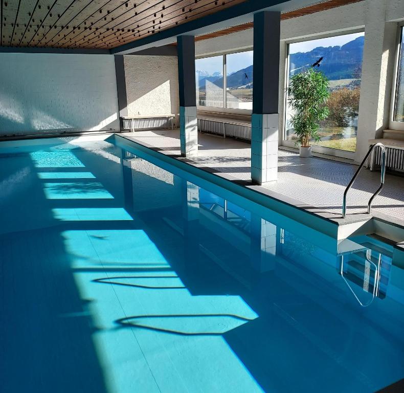 a swimming pool with blue water in a building at Ferienwohnung AllgOy in Oy-Mittelberg