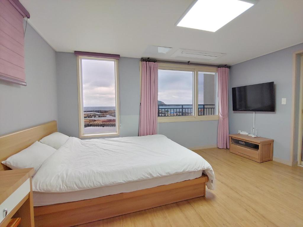 a bedroom with a bed and a flat screen tv at Eutteum-won Pension in Jeju
