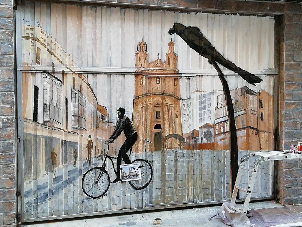 a painting of a man on a bike on a building at Apartamentos nova de abaixo 3 in Pontevedra