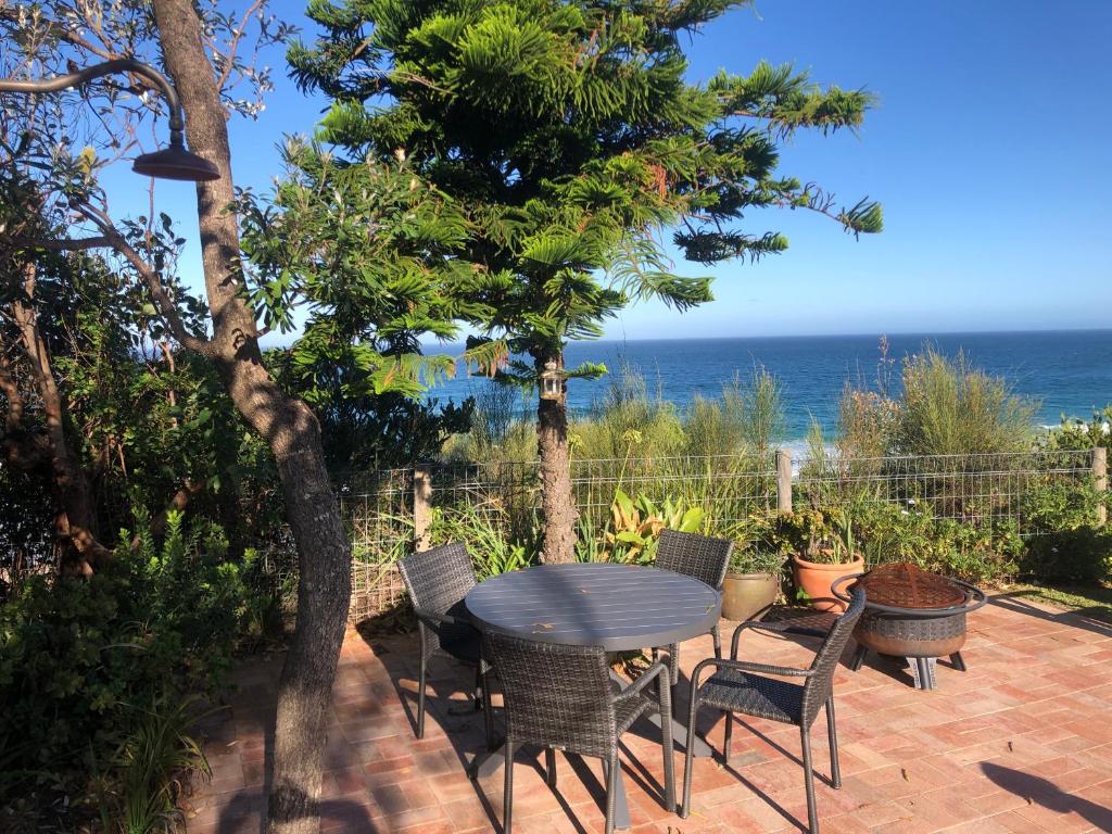 une terrasse avec une table et des chaises et l'océan dans l'établissement Ocean View Beachfront, à Bermagui