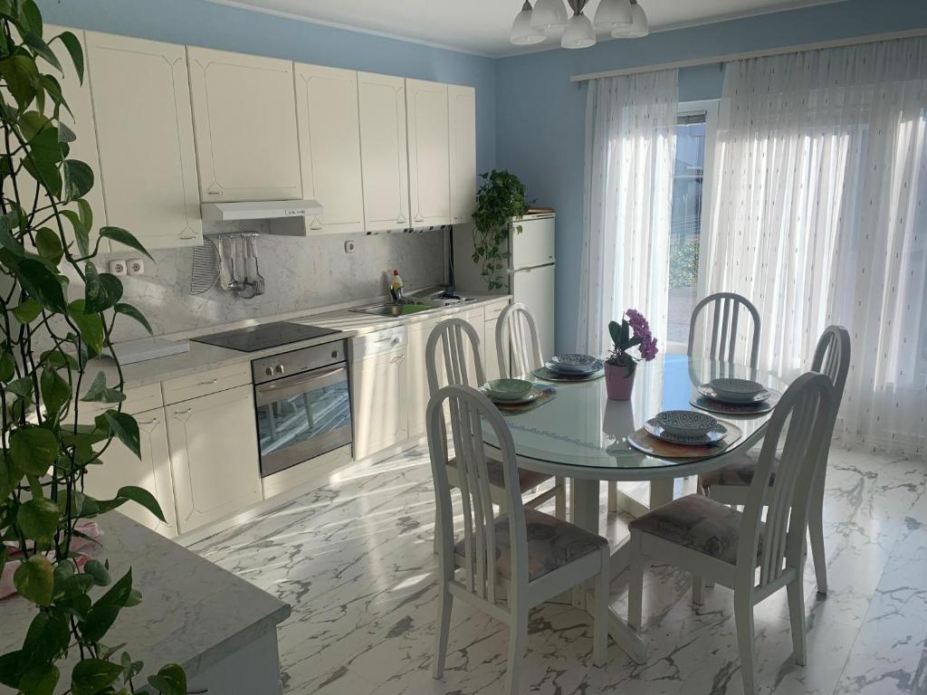 eine Küche mit einem Tisch und Stühlen sowie eine Küche mit weißen Schränken in der Unterkunft Sweet Home Apartment in Maribor