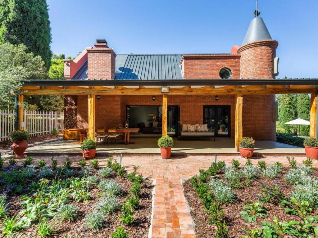 a brick house with a pavilion in a garden at Devon Castle Forest Lodge in Stellenbosch