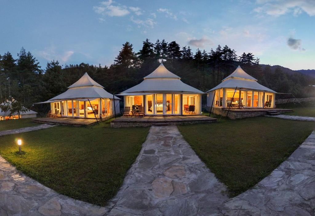 a large house with a lot of windows on a lawn at Tenzinling Luxury Villa Tents in Paro