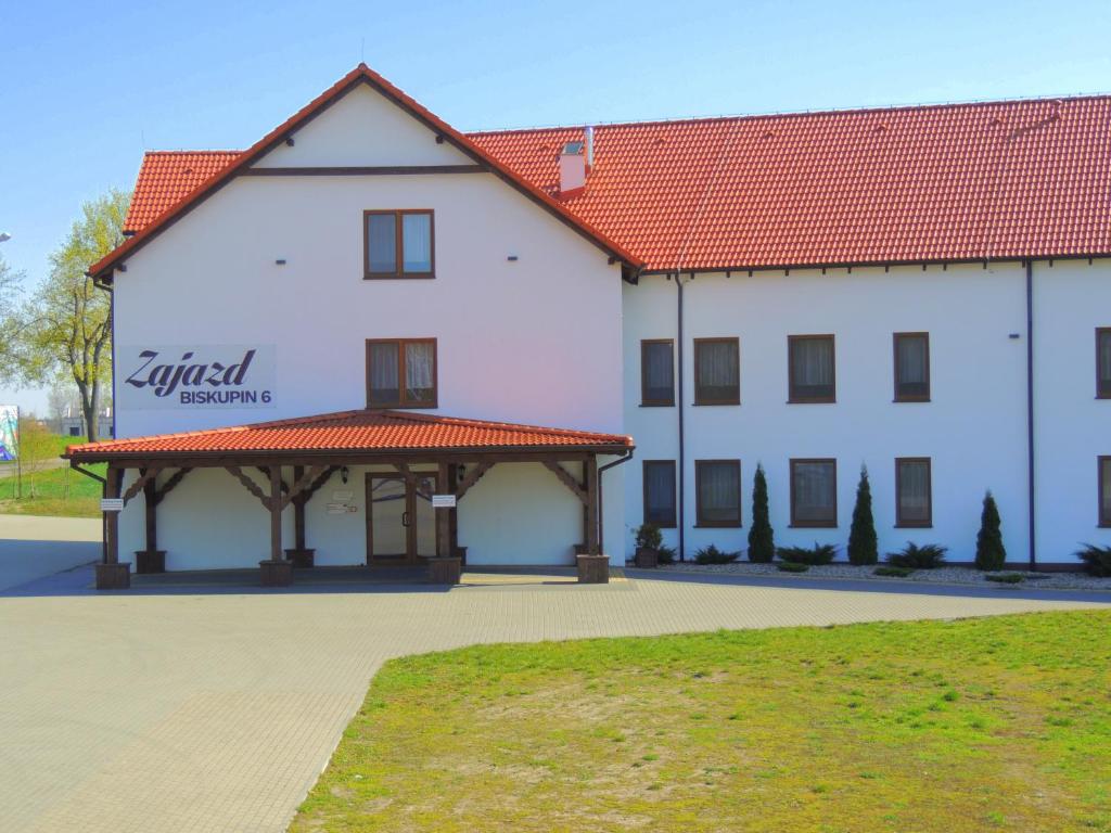 a large white building with a red roof at Zajazd w Biskupinie in Biskupin