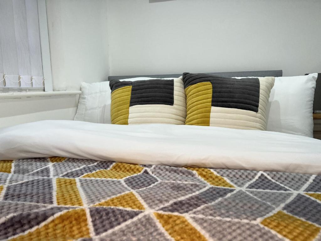a bed with yellow and black pillows on it at Urban Retreat - Bradford Apartment Gem in Bradford