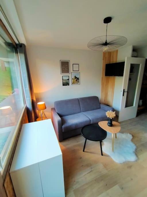 a living room with a blue couch and a table at Crest Voland, Le Cernix studio de standing rénové in Cohennoz