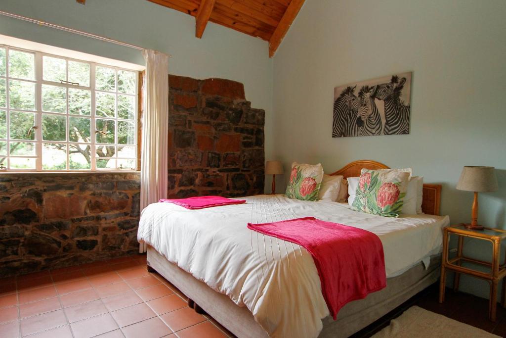 a bedroom with a bed with white sheets and a window at Spion Kop Lodge in Winterton