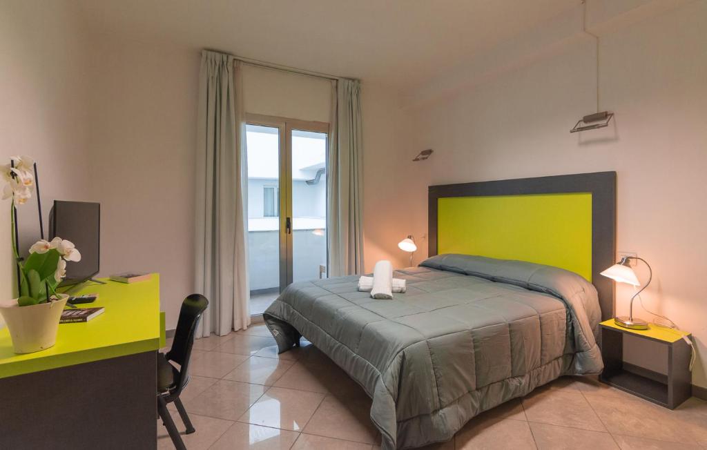 1 dormitorio con 1 cama con cabecero verde y escritorio en Delta Rooms, en Olbia