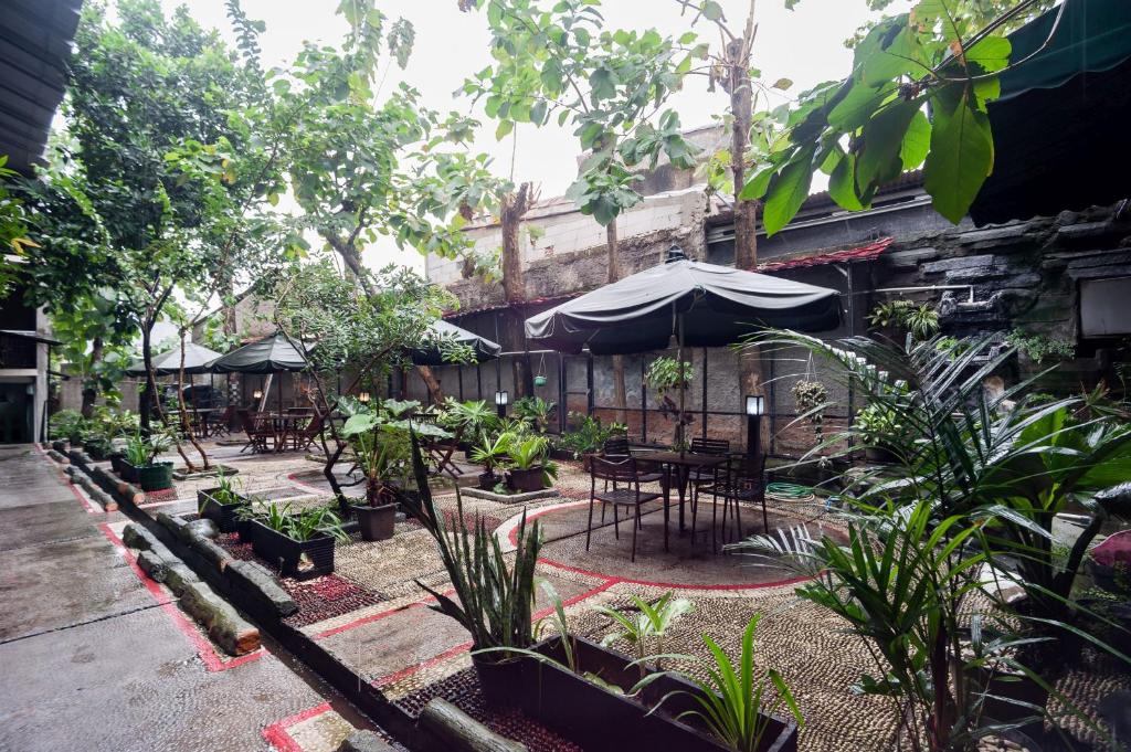 eine Außenterrasse mit Tischen, Stühlen und Pflanzen in der Unterkunft Safwah Bintaro Syariah Mitra RedDoorz in Tangerang