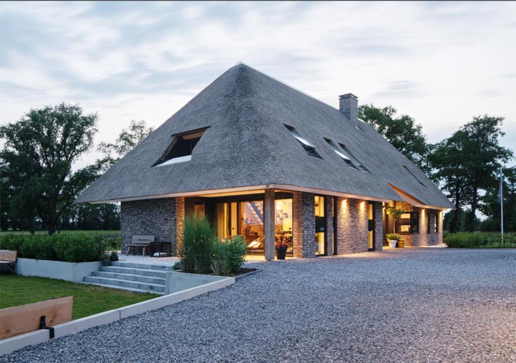 una casa con tetto di paglia e tetto di paglia. di B&B De Scheersehoeve a Holthone