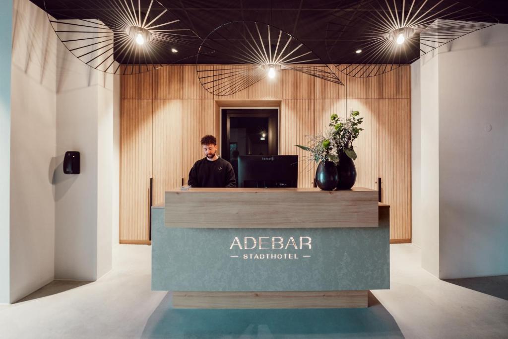 a man standing at a reception desk in a lobby at ADEBAR Stadthotel in Dingolfing