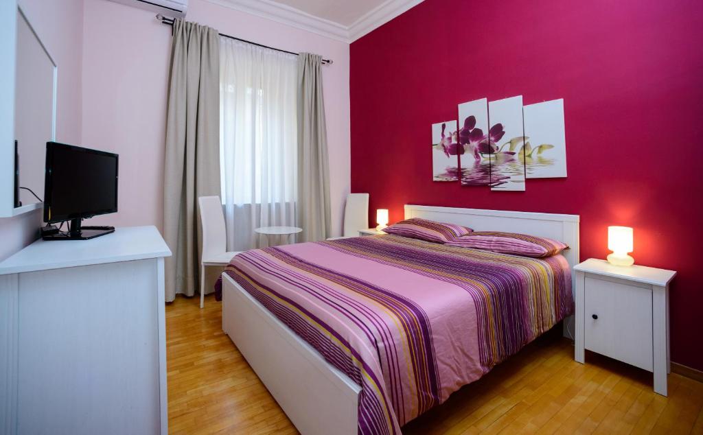 1 dormitorio rojo con 1 cama y TV en B&B Eternal Rome Inn, en Roma