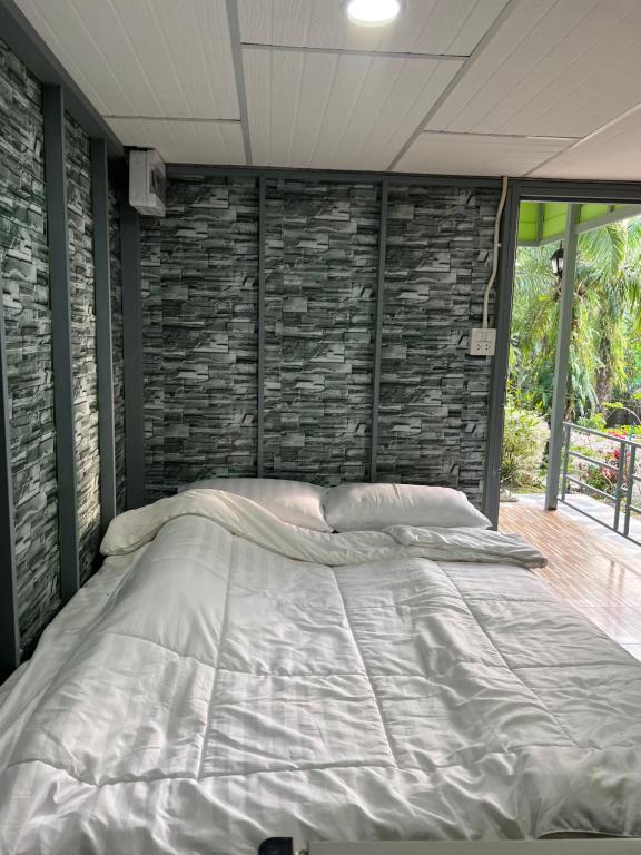un grande letto in una stanza con un muro di pietra di Baan Tarn Naam a Ban Lam Ru (1)