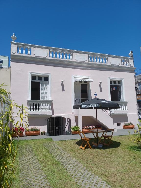 uma casa branca com uma mesa e um guarda-chuva em Casarão Hostel & Quartos Privados em Florianópolis