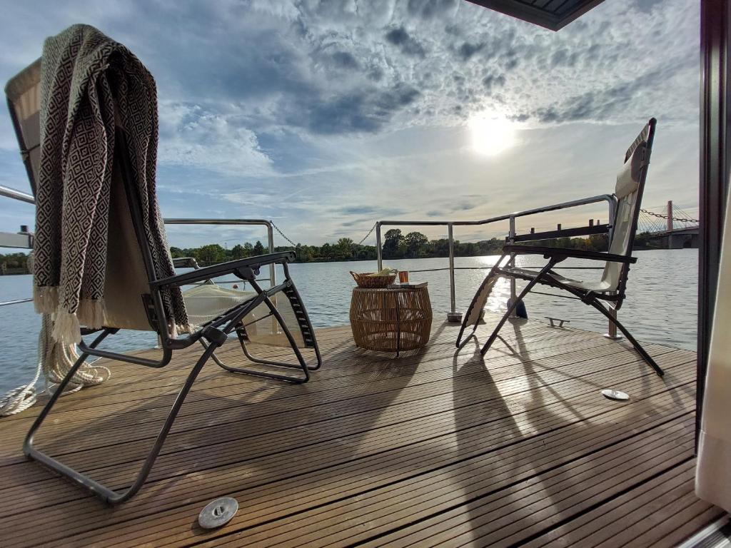 a couple of chairs sitting on the deck of a boat at Lemuria Houseboat - pływający domek na wodzie in Wrocław