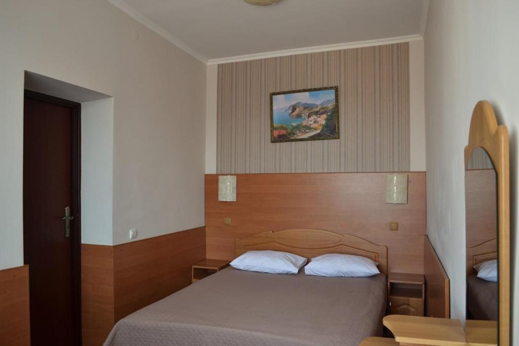 ein Schlafzimmer mit einem Bett mit einem Kopfteil aus Holz in der Unterkunft Hotel Perlyna ARS in Stryi