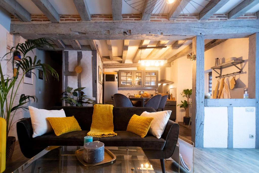 uma sala de estar com um sofá preto e almofadas amarelas em La Tour aux Grains chambres autonomes em Romorantin-Lanthenay