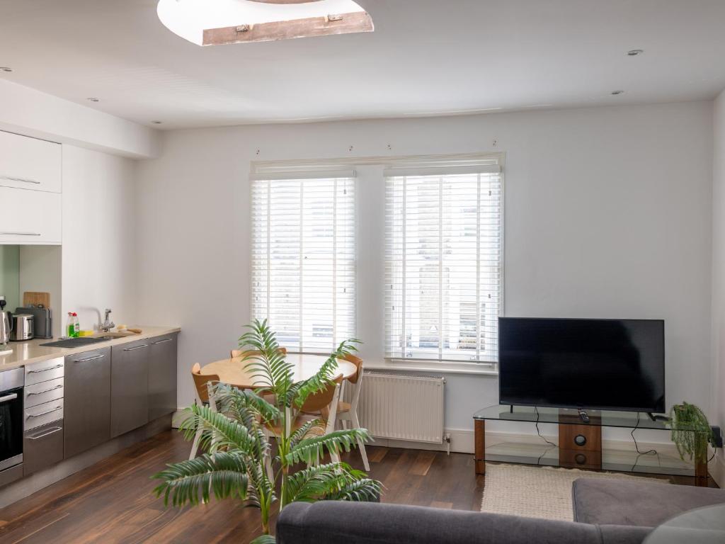 a living room with a flat screen tv and a kitchen at Pass the Keys - Top Floor Flat in the heart of Portobello Market, London in London