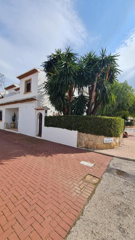 a white house with palm trees and a brick driveway at Casa Playa Javea in Jávea