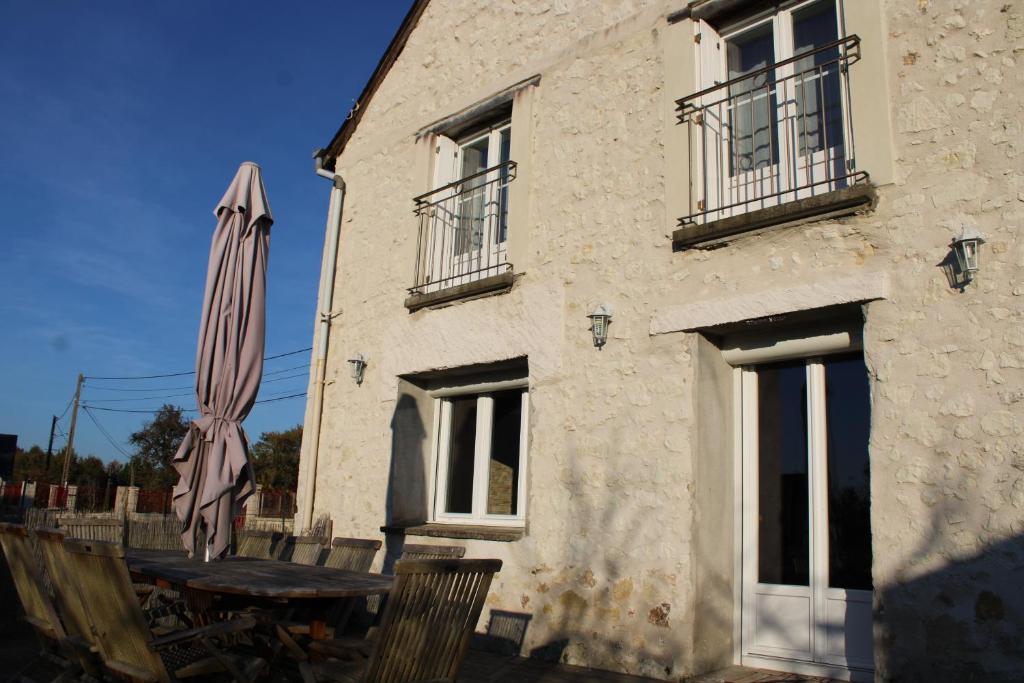 un bâtiment avec une table et un parasol devant lui dans l'établissement Gîte Natur'Amis, à Rivarennes