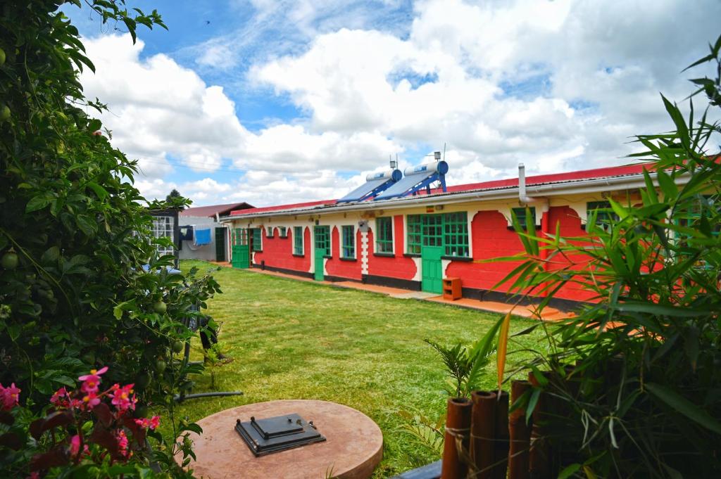 un edificio rojo y verde con un patio de césped en The Swiss Side Iten, en Iten