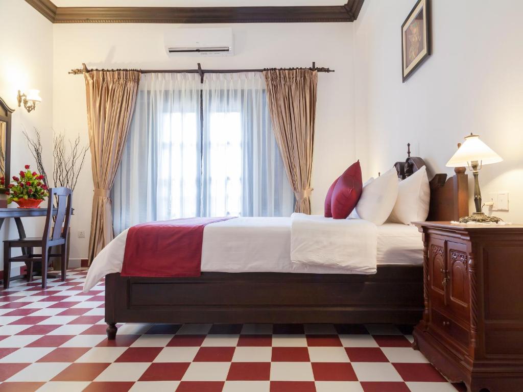 a bedroom with a bed and a checkered floor at Chateau d'Angkor La Residence in Siem Reap
