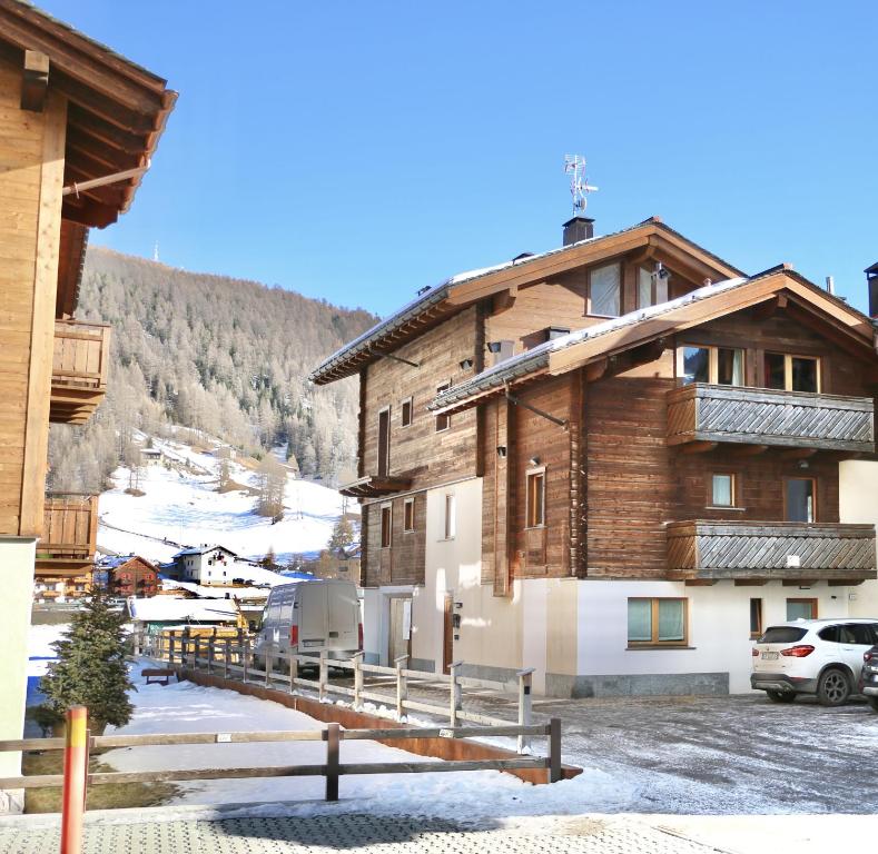duży drewniany budynek z śniegiem na ziemi w obiekcie Casa Severina w Livigno