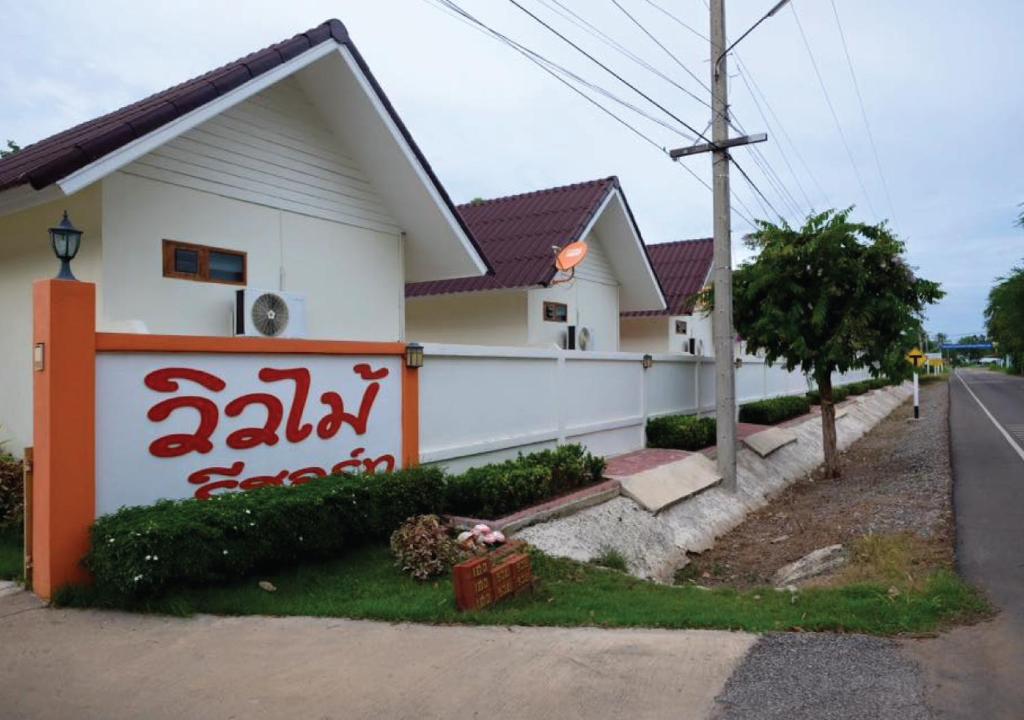 een wit huis met rode letters erop bij วิวไม้ รีสอร์ท in Ban Khao Sai