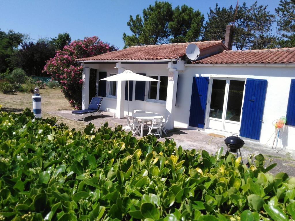 a cottage with a table and an umbrella at Maison oléronaise avec la plage à pied et la piste cyclable au bout du jardin in Dolus d'Oléron