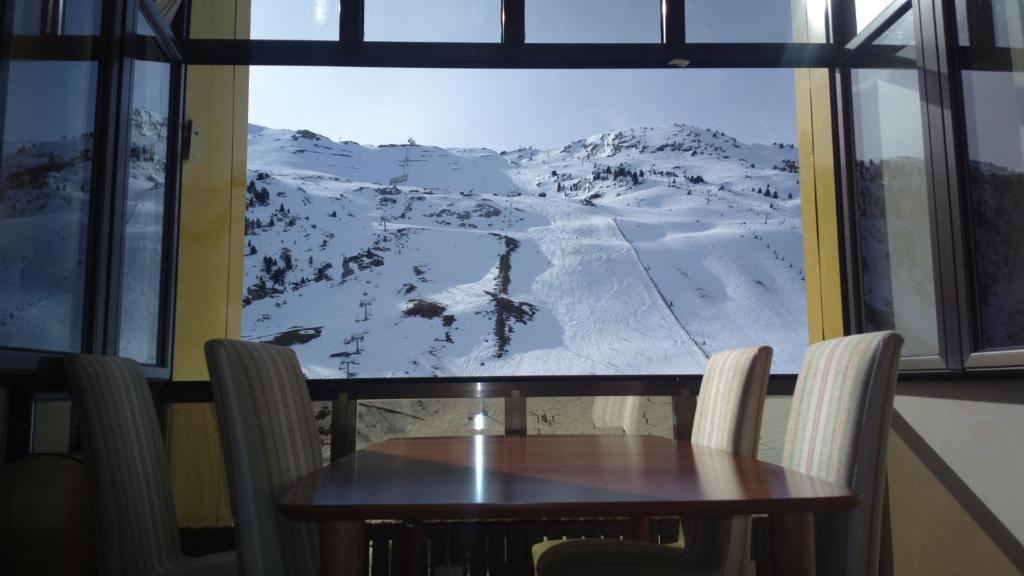 a table and chairs in front of a window with a mountain view at Tobazo Candanchú pie de pista in Candanchú
