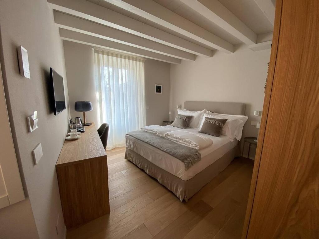 a white bedroom with a bed and a window at La torre in Belgirate
