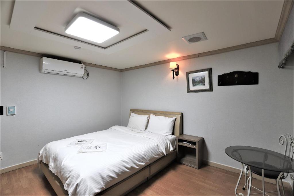 a bedroom with a bed and a table and a window at Hani Motel in Daejeon