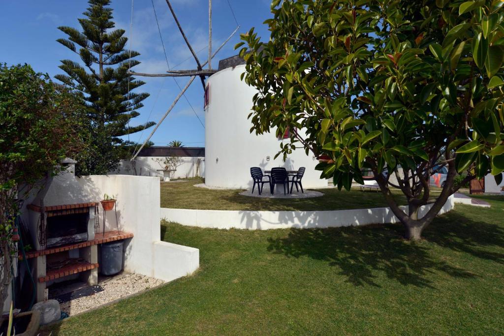 un patio trasero con mesa, sillas y un árbol en FLH Moinho do Mar en Ericeira