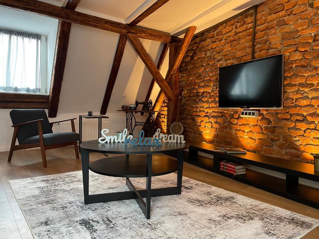 a living room with a table and a tv on a brick wall at Grich Witch apartment in Zagreb