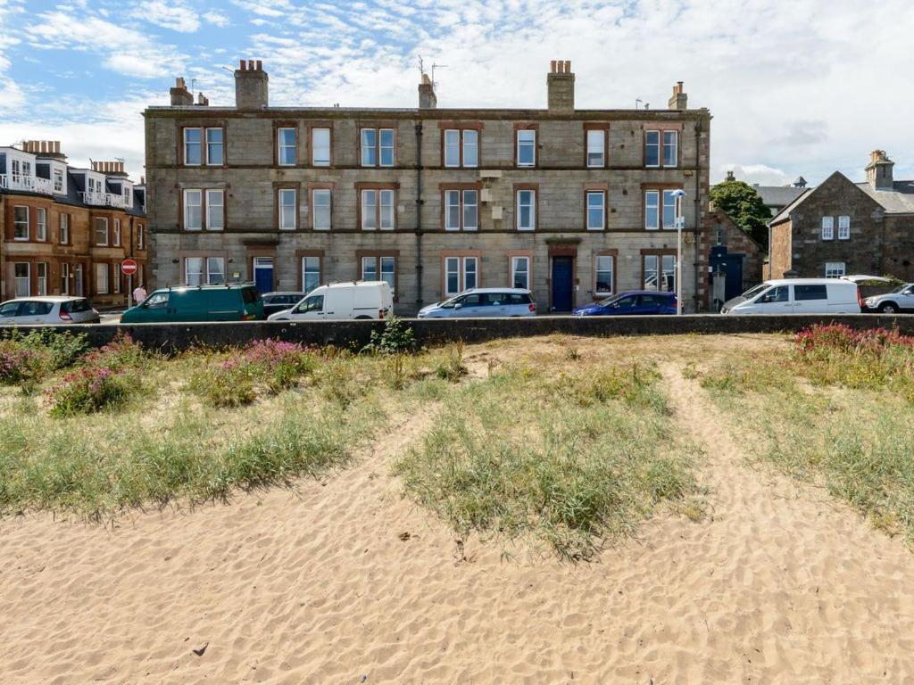 un edificio con coches estacionados frente a una playa en Driftwood en North Berwick