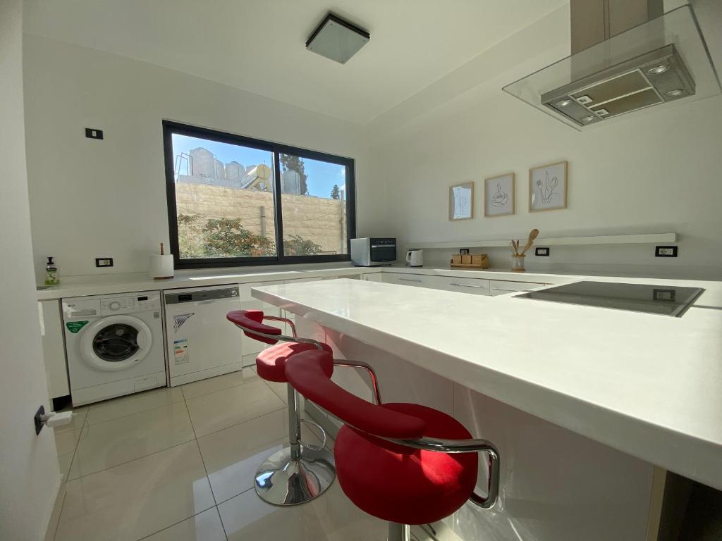 a kitchen with a white counter and a red chair at Lemon Tree Residence in Amman