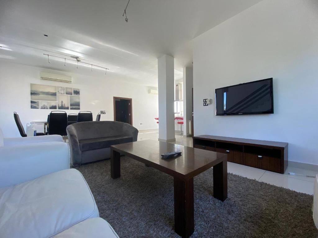 a living room with a couch and a tv on a wall at Lemon Tree Residence in Amman
