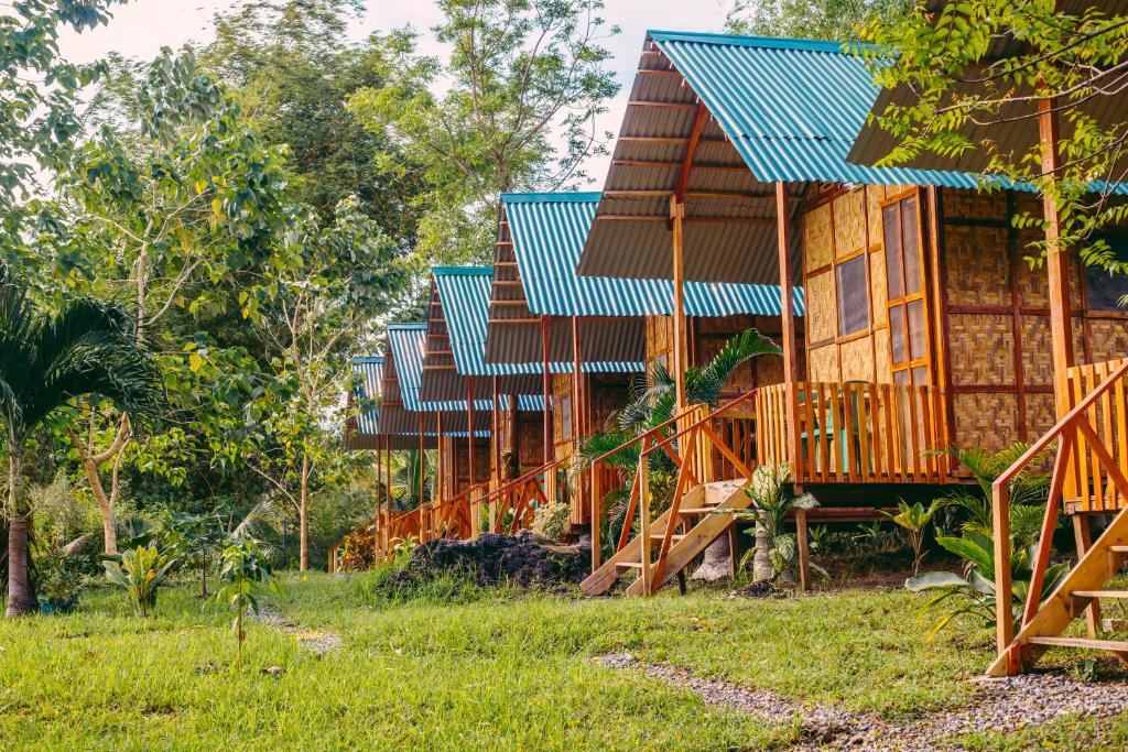a row of wooden houses with blue roofs at Green Acres Village in Moalboal