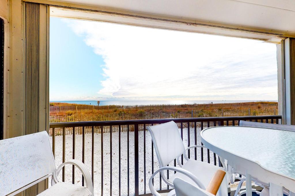 a balcony with a table and chairs and a view of the ocean at Sandpiper Dunes 109 in Ocean City
