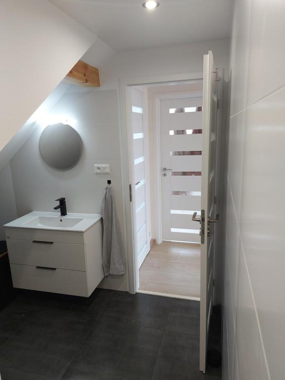 een badkamer met een wastafel, een spiegel en een deur bij Apartman Barbara in Lipany