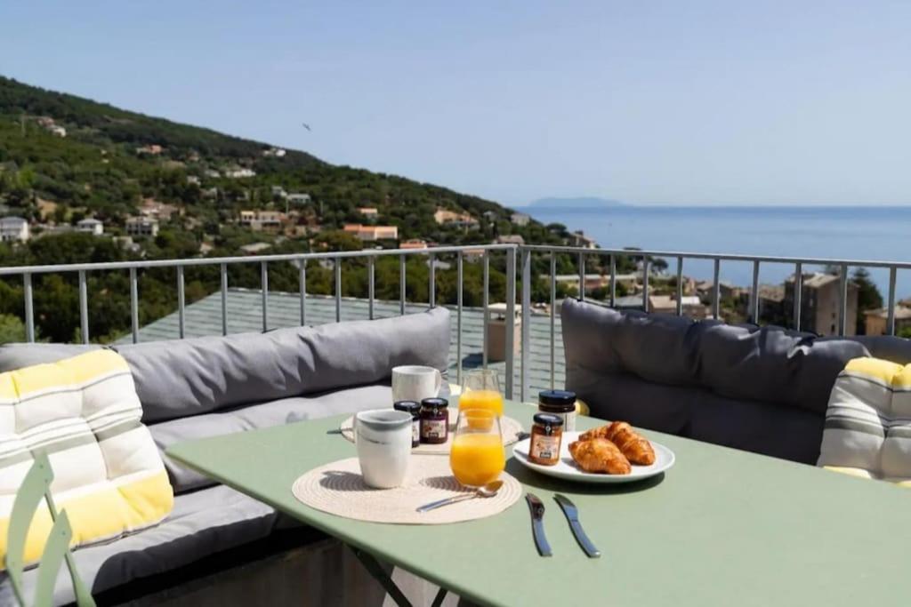 een tafel met een bord eten op een balkon bij Casa Lunga à Erbalunga- A deux pas de la plage in Brando