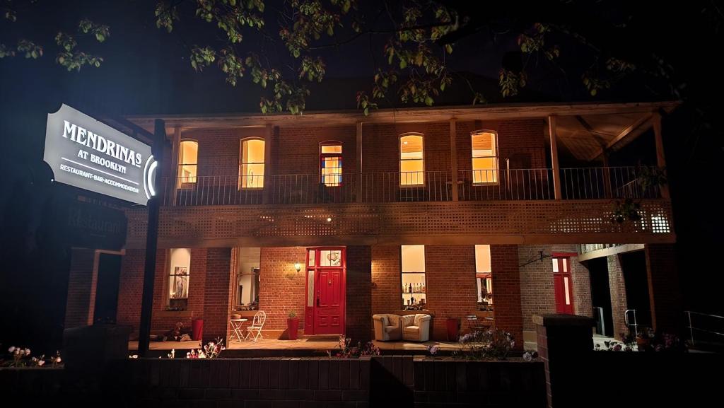 un edificio de ladrillo con una puerta roja por la noche en Mendrinas at Brooklyn en Tumut