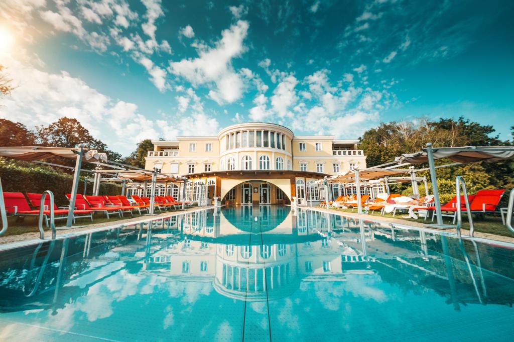 einen Pool in einem Resort mit roten und weißen Sonnenschirmen in der Unterkunft Hotel BEI SCHUMANN in Kirschau