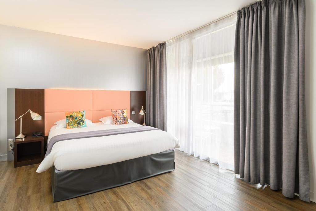 1 dormitorio con cama grande y ventana grande en Hype Hôtel, en Biscarrosse