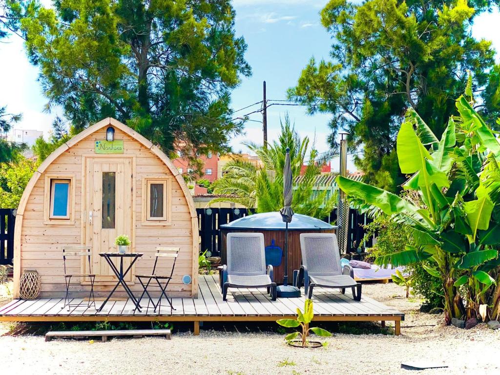 a small wooden house with two chairs and a table at Nashira HOT TUB PISCINA SAUNA Y JARDIN in Buzanada