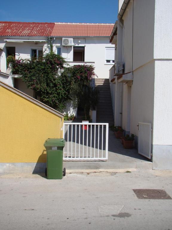 a green trash can sitting in front of a building at Apartment Tičić in Povljana