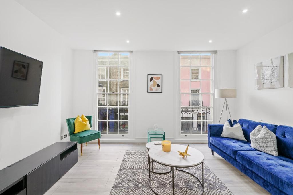 ein Wohnzimmer mit einem blauen Sofa und einem Tisch in der Unterkunft Hububb Luxury Knightsbridge Apartments in London